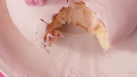 pink glazed cream filled donut with a bite taken out of it