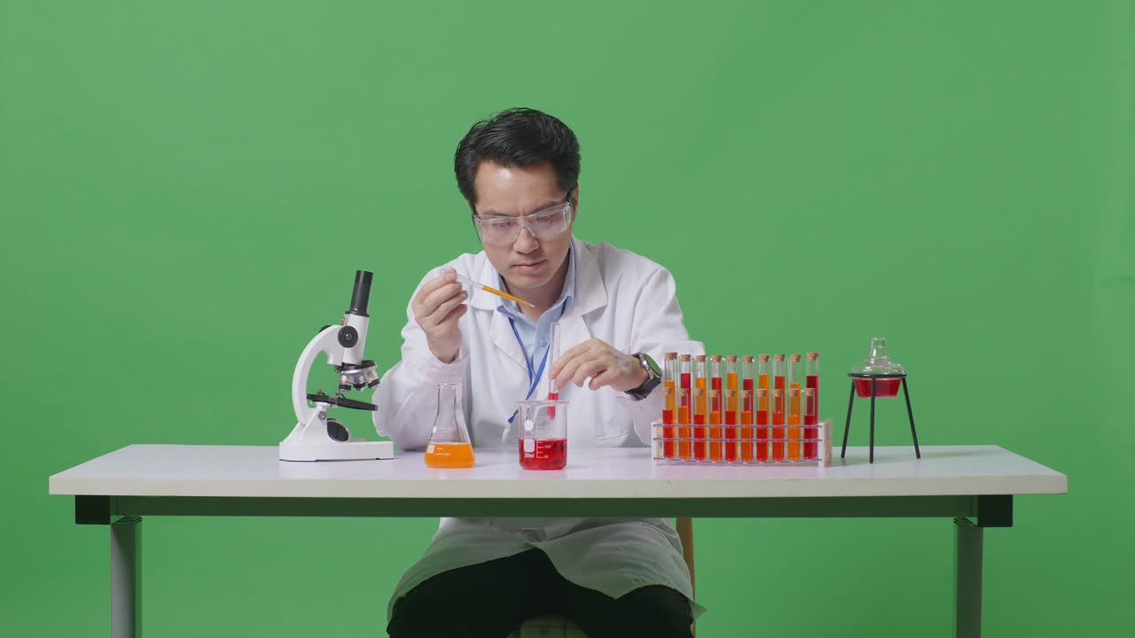 Asian Man Scientist Making Experiment With Test Tube And Saying Wow While Working On The Table With Microscope In The Green Screen Background Laboratory