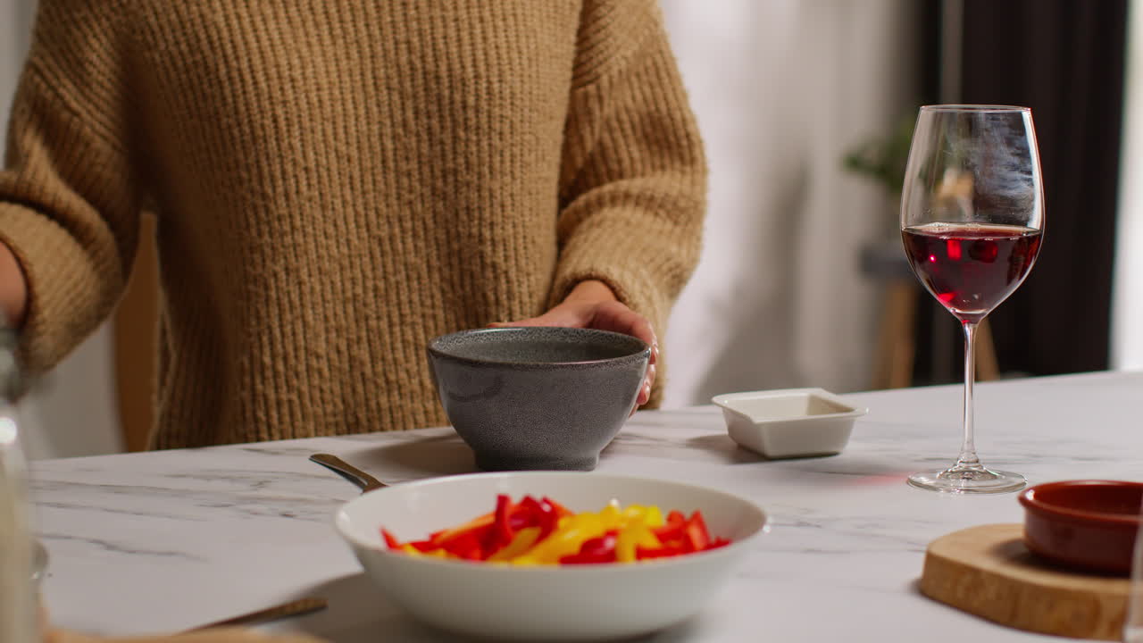 близкий взгляд на женщину дома на кухне, готовящую здоровую вегетарианскую или веганскую еду, едя миску салата табуле с бокалом вина 1