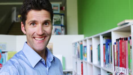 Profesor-De-Escuela-Tomando-Un-Libro-De-La-Estantería-De-La-Biblioteca-De-La-Escuela