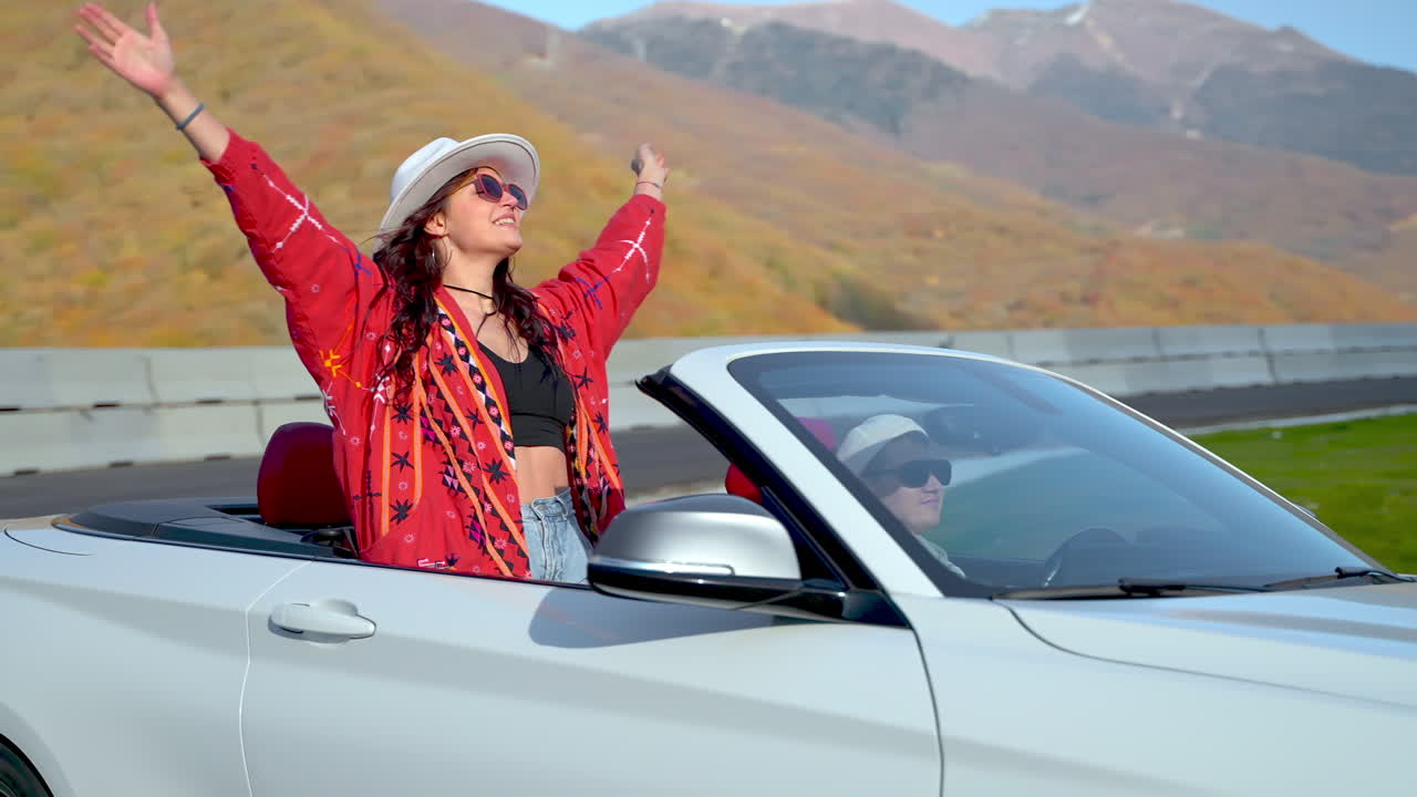 한 부부는 가을 잎자루를 통해 컨버터블에서 경치 좋은 드라이브를 즐기고 있습니다.