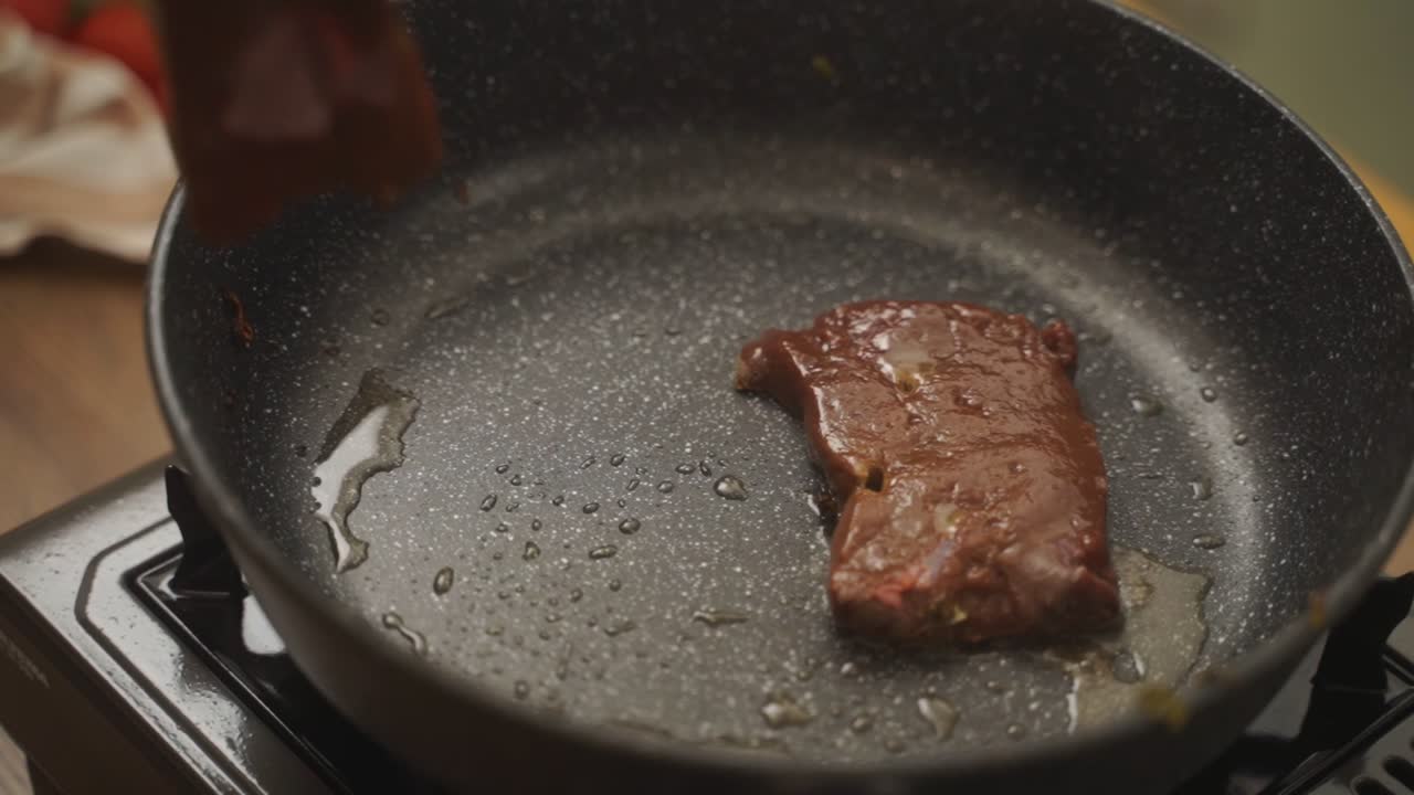 Unrecognizable cook frying roasted meat in pan