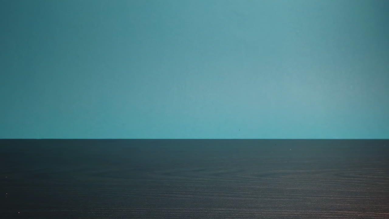 Close-up slowmotion of moving tomato on the desk in front of a blue background