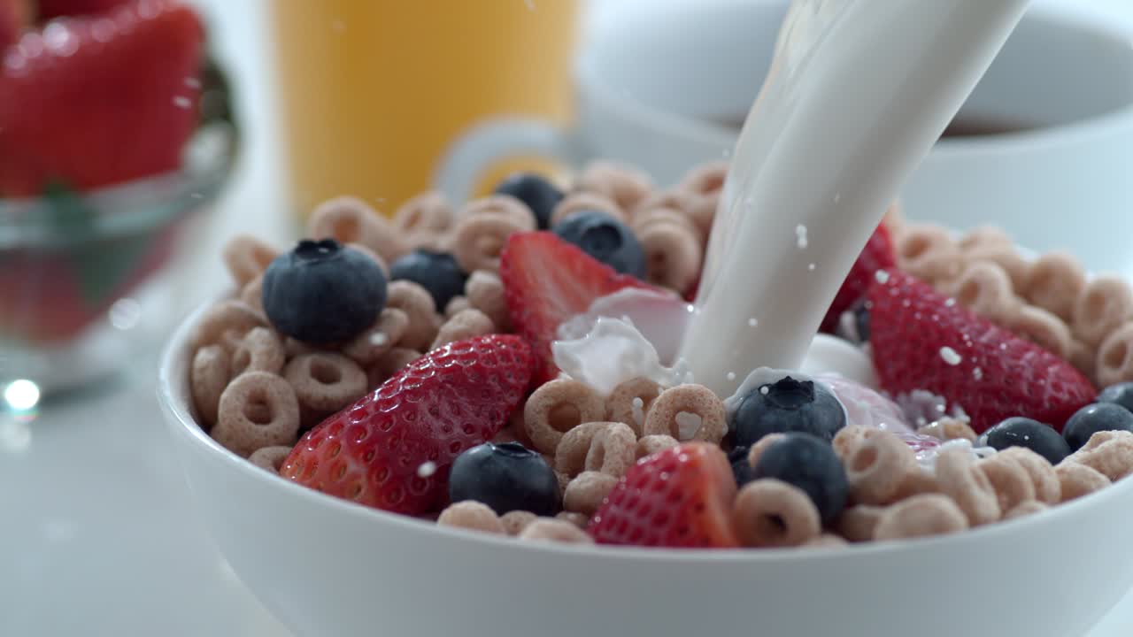 leche vertiendo en un cuenco de cereales con bayas, cámara lenta