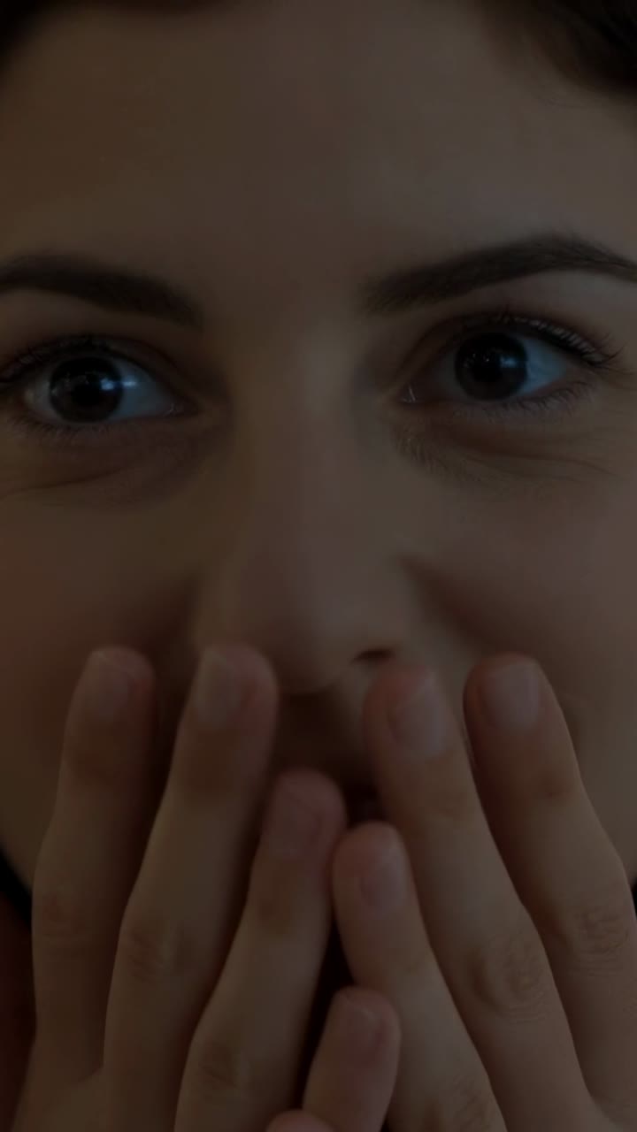 Video verticale: sentendo un rumore fuori campo, donna che si porta le mani alla bocca e poi le abbassa in studio