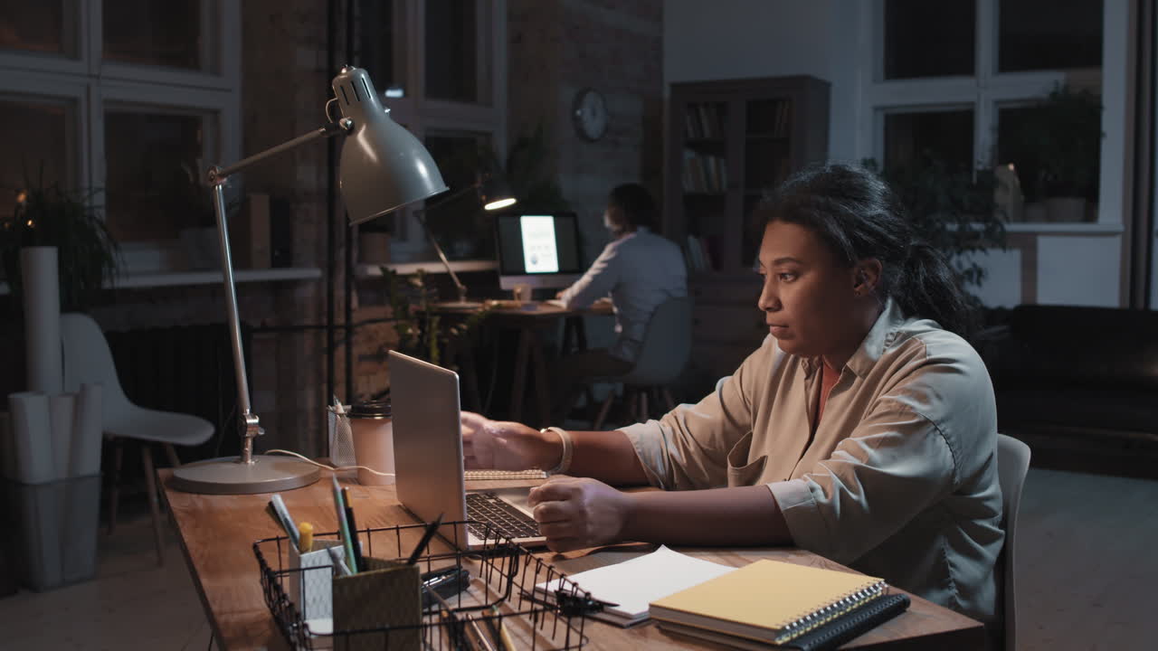Woman working late night on laptop in a dimly lit office