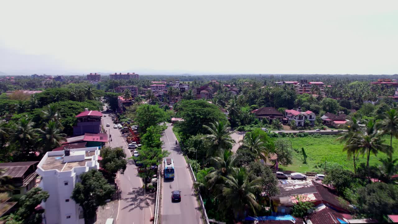 Sobrevoo de área rural com veículos em movimento e vegetação em Colva, Goa, Índia. Durante o dia, plano de aproximação, tomada de drone, em 4K.