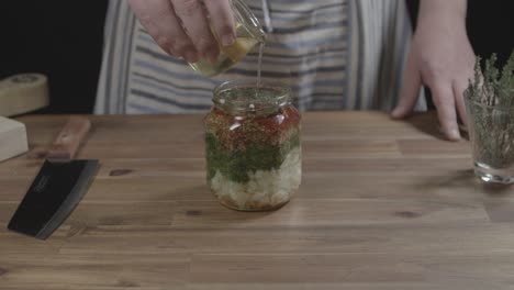 Add-oil-to-a-glass-container-with-ingredients-to-prepare-argentine-chimichurri,-sauce-for-barbecues