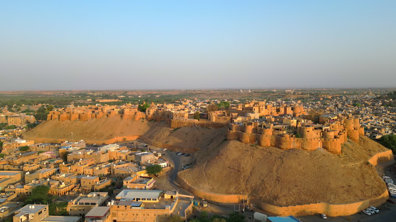 una toma de drone elevadora del fuerte de jaisalmer, destacando su majestuosa arquitectura de piedra arenisca dorada, rodeada de casas tradicionales rajasthan india 4k