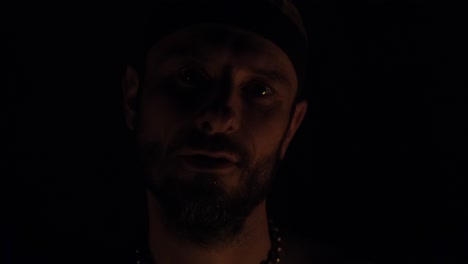 portrait of a male fire performer's face as he juggles fire balls that light up his face