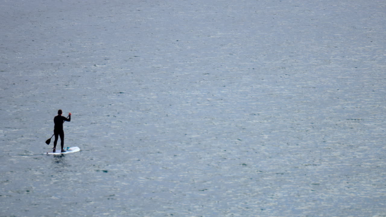 Distant view of a man standup paddle boarding on the sea
