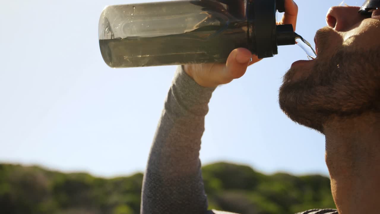 hombre triatleta bebiendo agua en un día soleado
