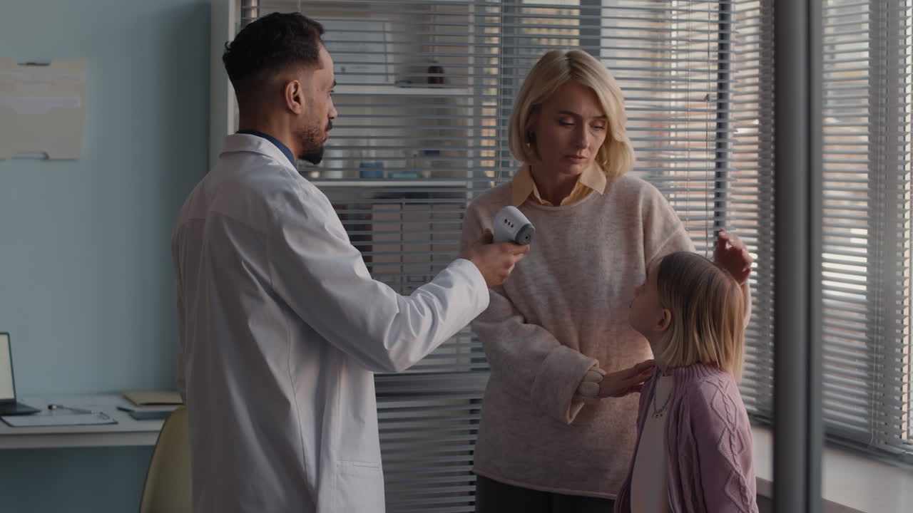 Doctor checks child's temperature with mother present