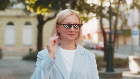 happy rich mature business woman putting on thug life sunglasses showing euro money on city street