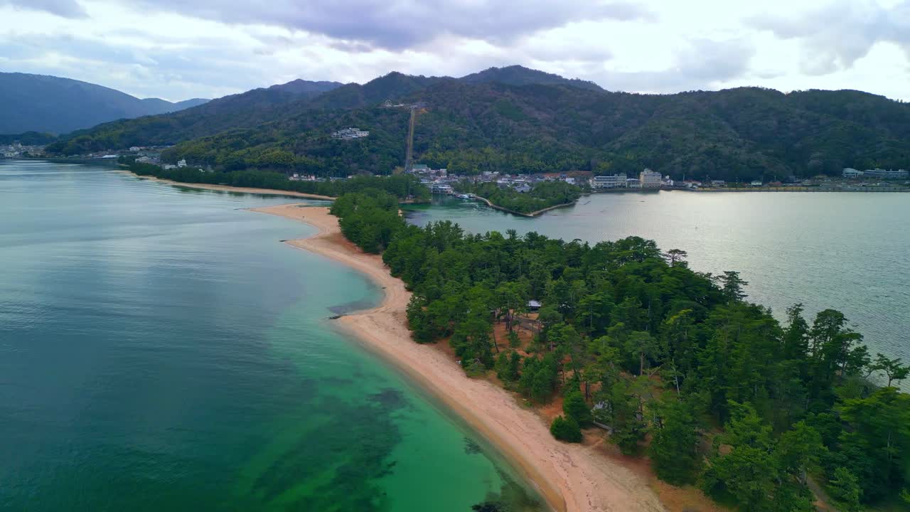 Flying foward drone shot of Amanohashidate pine-covered sandbar one of Japan's three famous scenic views, links both sides of Miyazu Bay in northern Kyoto Prefecture.
