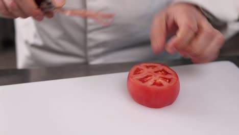 셰프가 토마토를 잘라내고 있습니다.