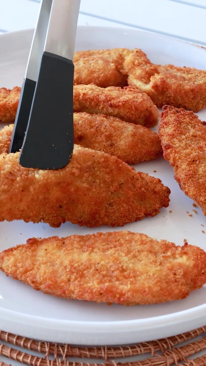 Crispy fried chicken pieces arranged on a white plate, captured with natural lighting and close-up shots