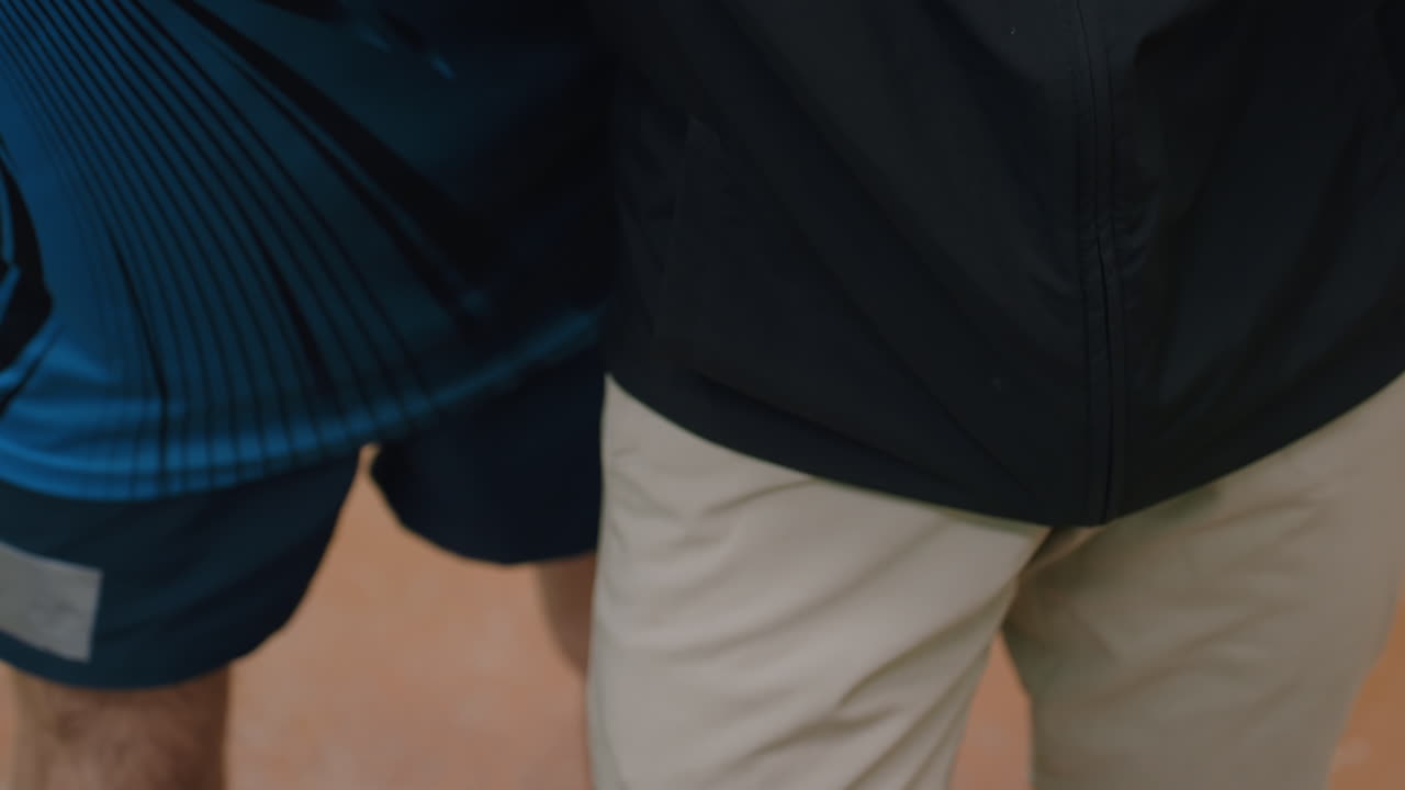 Close up moment during tennis training session as player receives hands on guidance to learn proper movement and striking technique for improving control and accuracy in game play