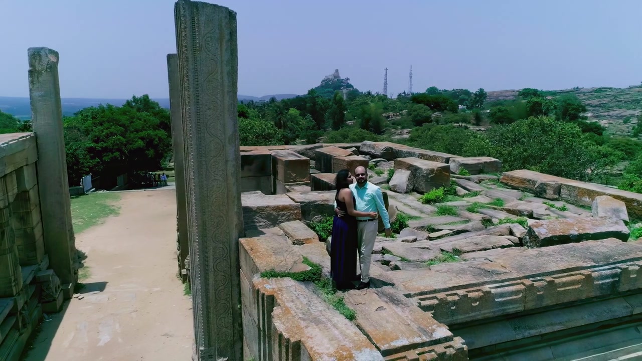 Coppia romantica si abbraccia tra antiche rovine in pietra con vista su un paesaggio verde