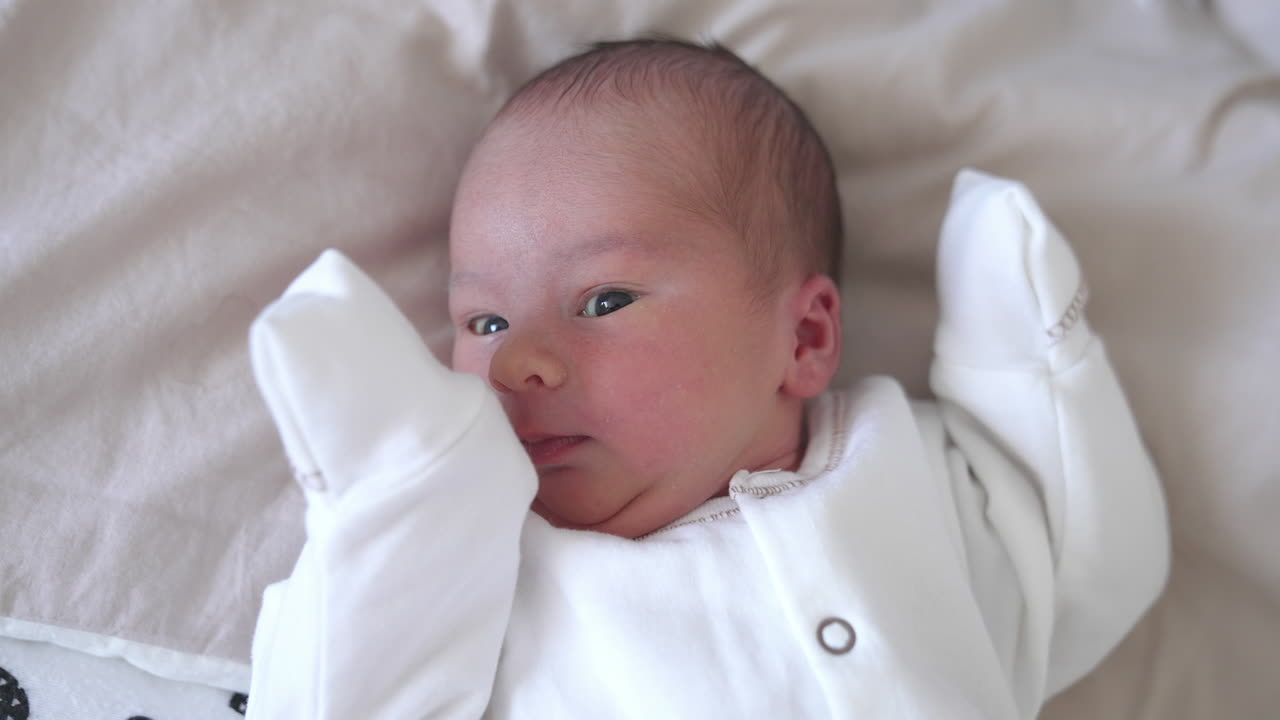 Funny infant. Adorable newborn baby sleeping and yawning on bed. Lovely toddler at home. Close-up