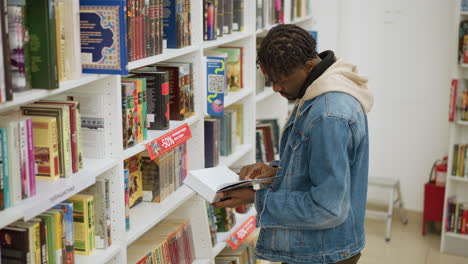 young man browsing bookshelves in modern library, holding book, focusing on selection, surrounded by colorful book covers, bright indoor lighting, cozy library atmosphere