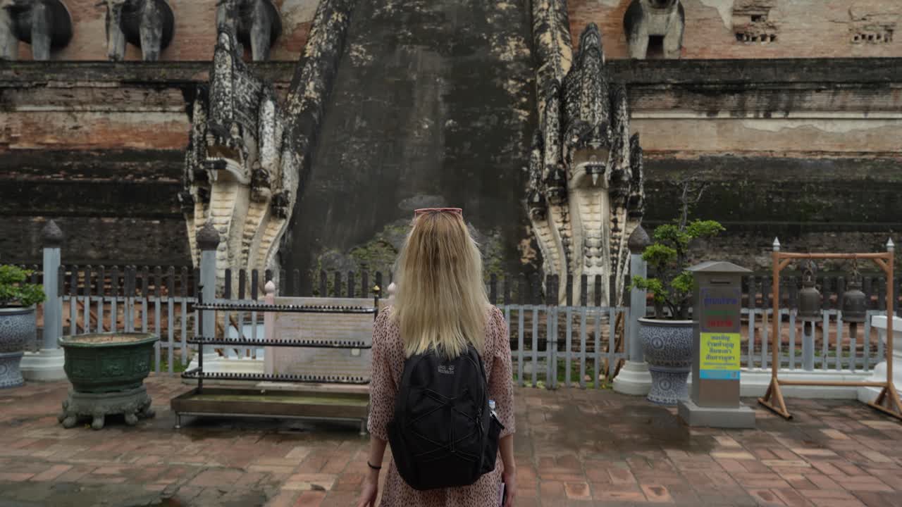 Young woman walking towards steps of Wat Chedi Luang Temple - Chiangmai Thailand