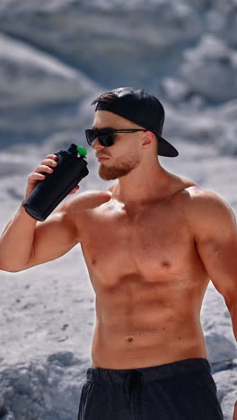 bodybuilder resting and drinking protein shake after exercising. concept of sport outdoors. vertical video