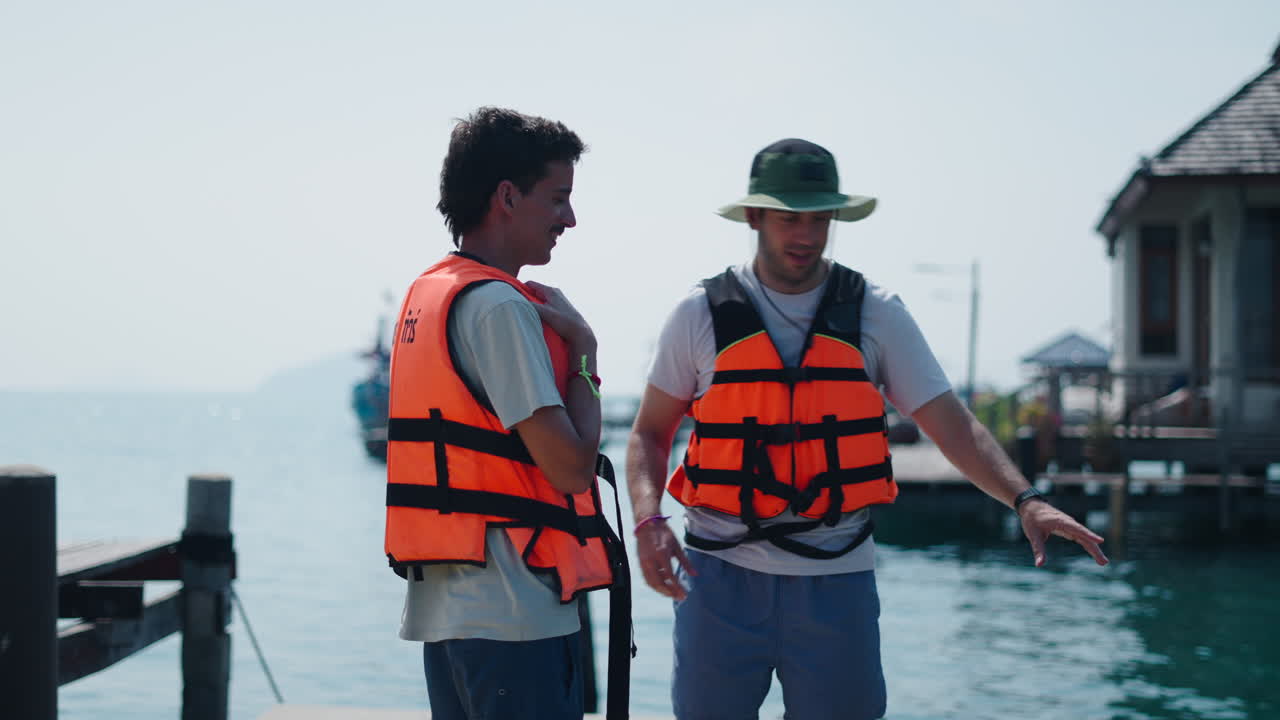 Dos personas con chalecos salvavidas cerca del agua