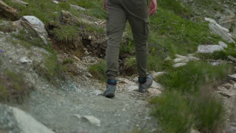 low angle close-up of unrecognizable man legs hiking mountain trail, static