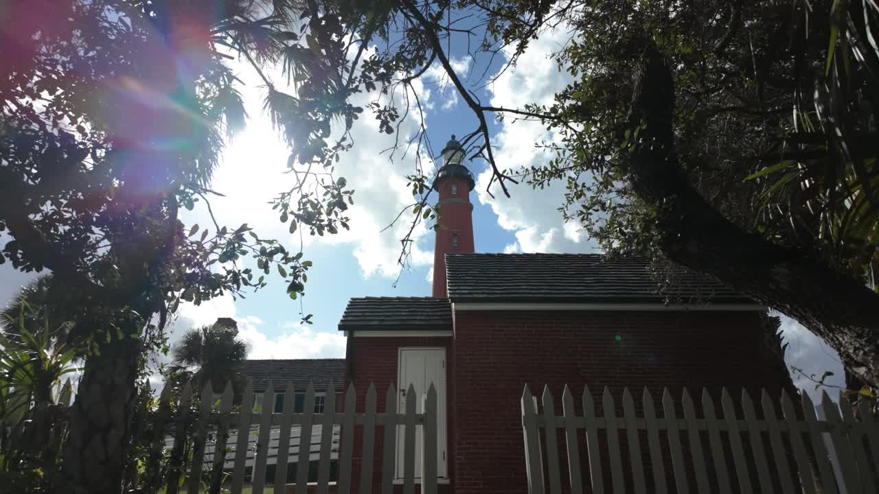 조용한 야외 환경 속에서, 화염등이 있는 웅장한 벽돌 건물이 높이 서 있으며, 색 울타리로 여 있으며, 광활한 하늘과 지나가는 구름을 한눈에 볼 수 있는 창문으로 장식되어 있습니다.