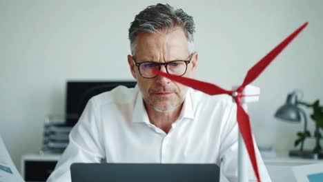 focused senior engineer working on a wind energy project in a modern office