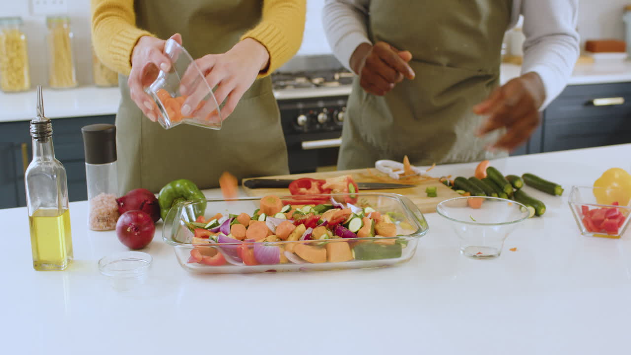 Preparing colorful vegetable dish, multiracial couple cooking together in modern kitchen, at home