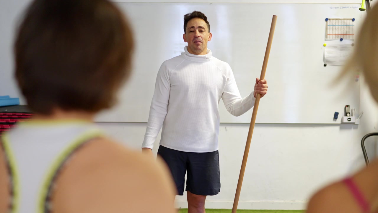 Fitness Instructor Leading a Group Exercise Class with Wooden Poles