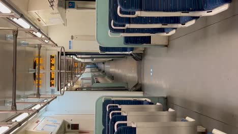 Empty-train-interior-with-blue-seats-and-white-walls,-vertical-shot