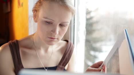 Mädchen-Liest-Ein-Buch-Am-Fenster