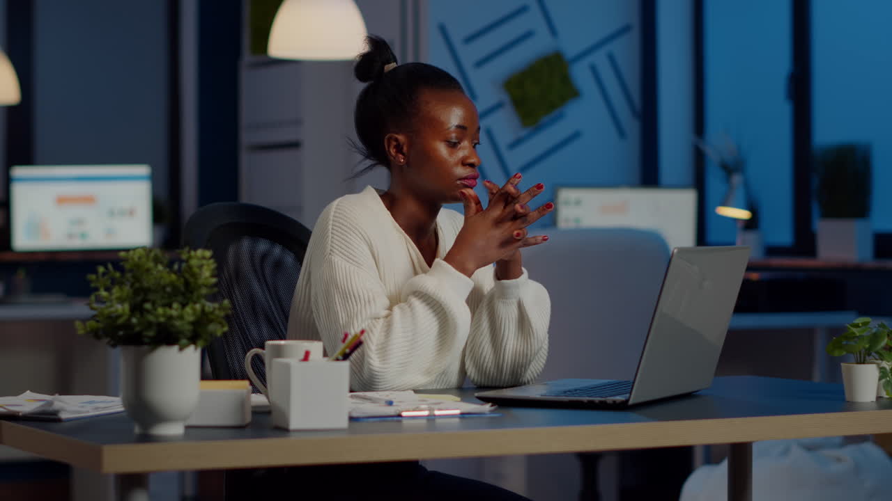 Overworked african manager woman massaging head while sitting at workplace