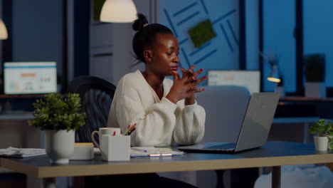 Overworked-african-manager-woman-massaging-head-while-sitting-at-workplace