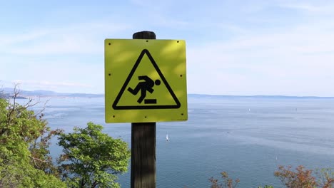 Toma-Panorámica-Del-Cartel-Que-Muestra-El-Peligro-De-La-Caída-En-El-Sendero-Sobre-La-Orilla-Del-Mar