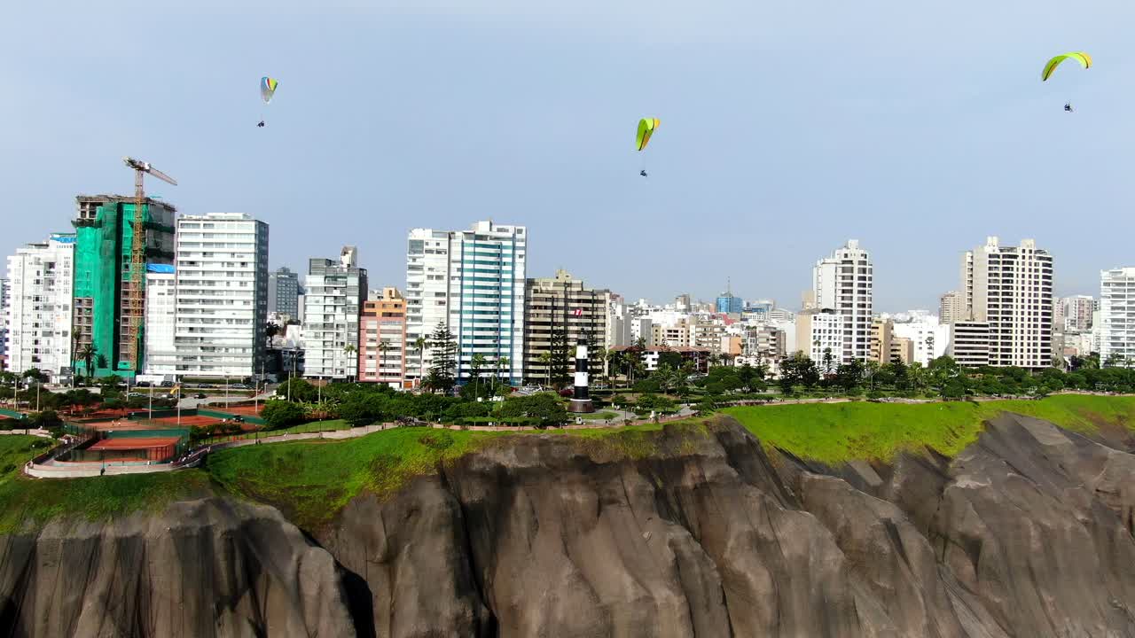 페루의 미라플로레스 (miraflores) 의 푸른 지역인 태평양 연안에서 날아다니는 3개의 패러글라이더의 4k 항공 영상.
