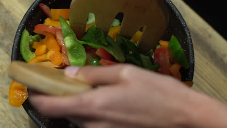 close up of female hands mixing salad bowl contents