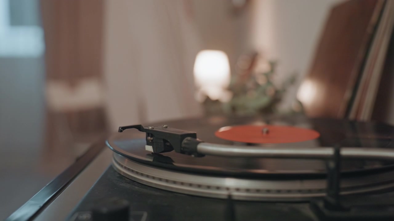 Vinil girando no toca-discos, brilho quente do abajur e figura borrada balançando, agulha traçando o sulco enquanto o disco gira, ritmo íntimo e foco suave, clima vintage romântico, interior aconchegante, trilha sonora
