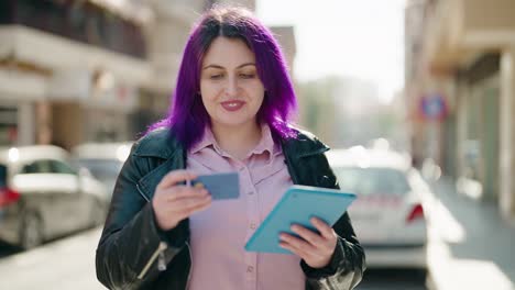 mujer joven de tamaño plus usando touchpad y tarjeta de crédito en la calle
