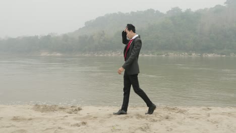 businessman walking along riverbank on a foggy day