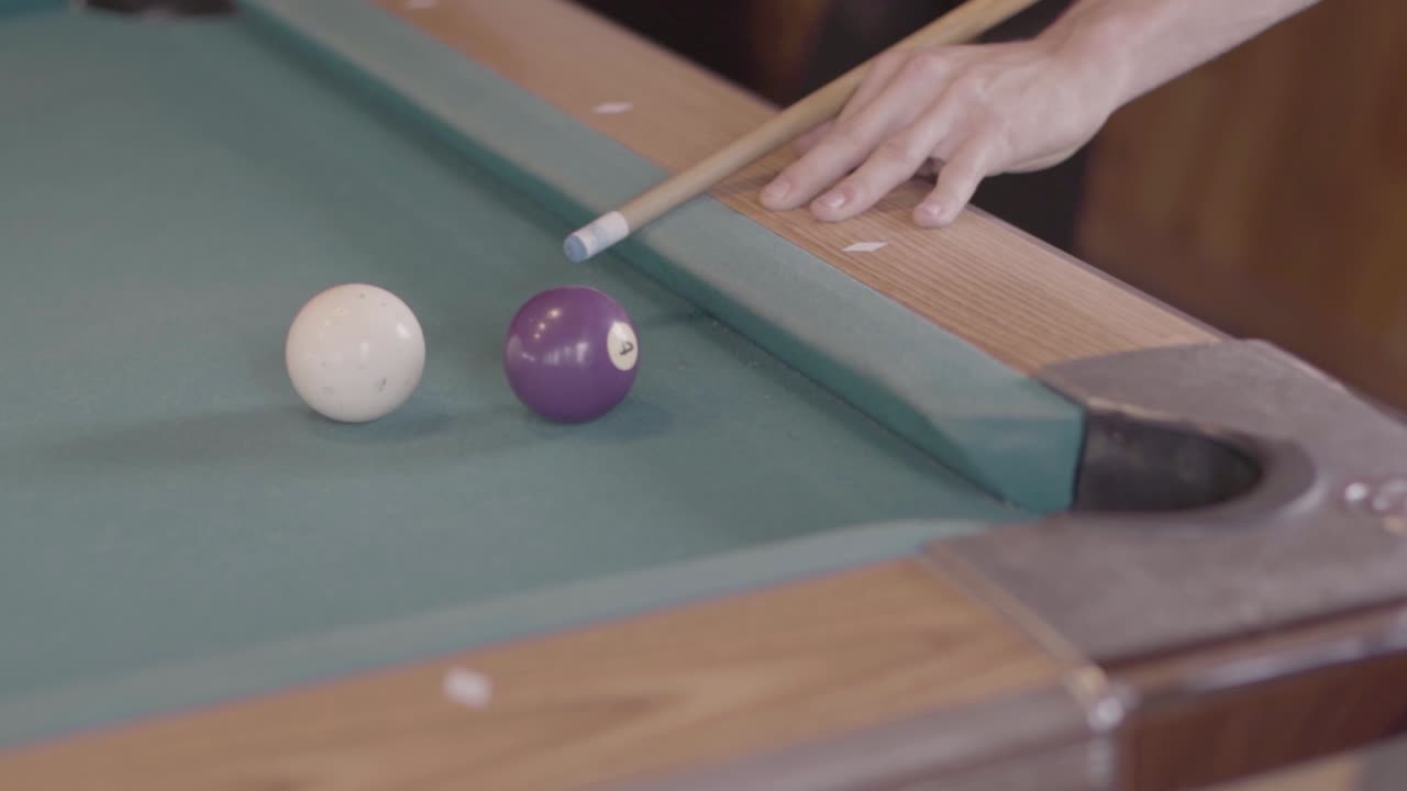 Hitting white ball in biliard game on green table in slow motion. Hand held shot
