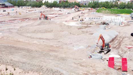 uk town housing development diggers working foundation construction site aerial view slow left orbit low