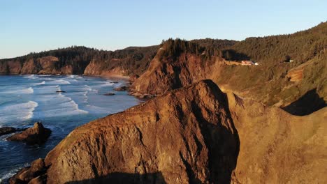 drone flies up and over cliff at the beach at golden hour