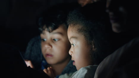 familia usando computadora tablet por la noche niños jugando juegos en pantalla táctil con madre y padre enseñando a los niños viendo entretenimiento divirtiéndose antes de acostarse