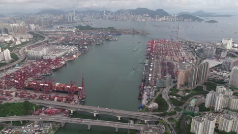 Weitwinkel,-Höhenaufnahme-Des-Industriehafens-Und-Der-Skyline-Von-Hongkong-Im-Hintergrund-An-Einem-Bewölkten-Tag