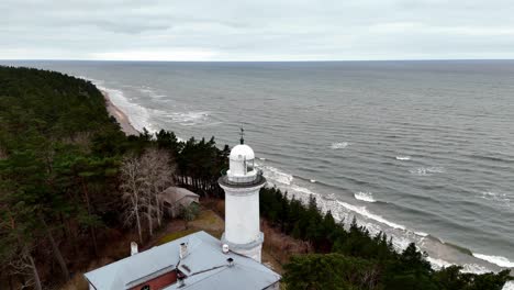 a lighthouse in uzava is on a rocky baltic sea shoreline, large body of water in the background