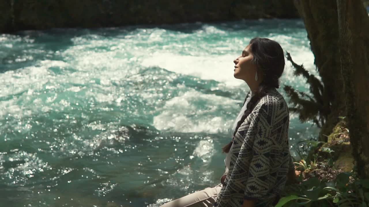mujer relajándose junto a un río de montaña